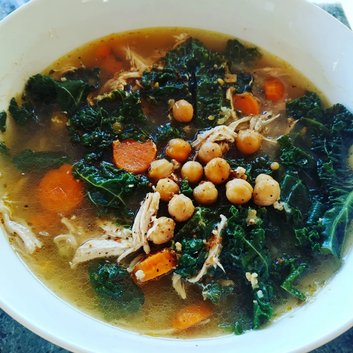 A close-up shot of hearty Chicken Kale Soup with Crispy Chickpeas, showcasing tender chicken and vibrant kale.