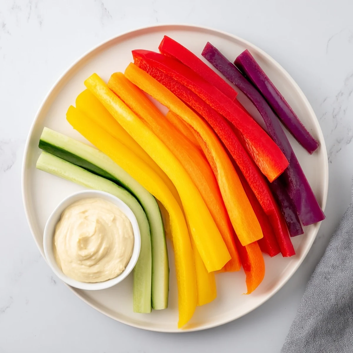 Fresh rainbow arch veggie sticks arranged beautifully, ready to dip in creamy hummus.