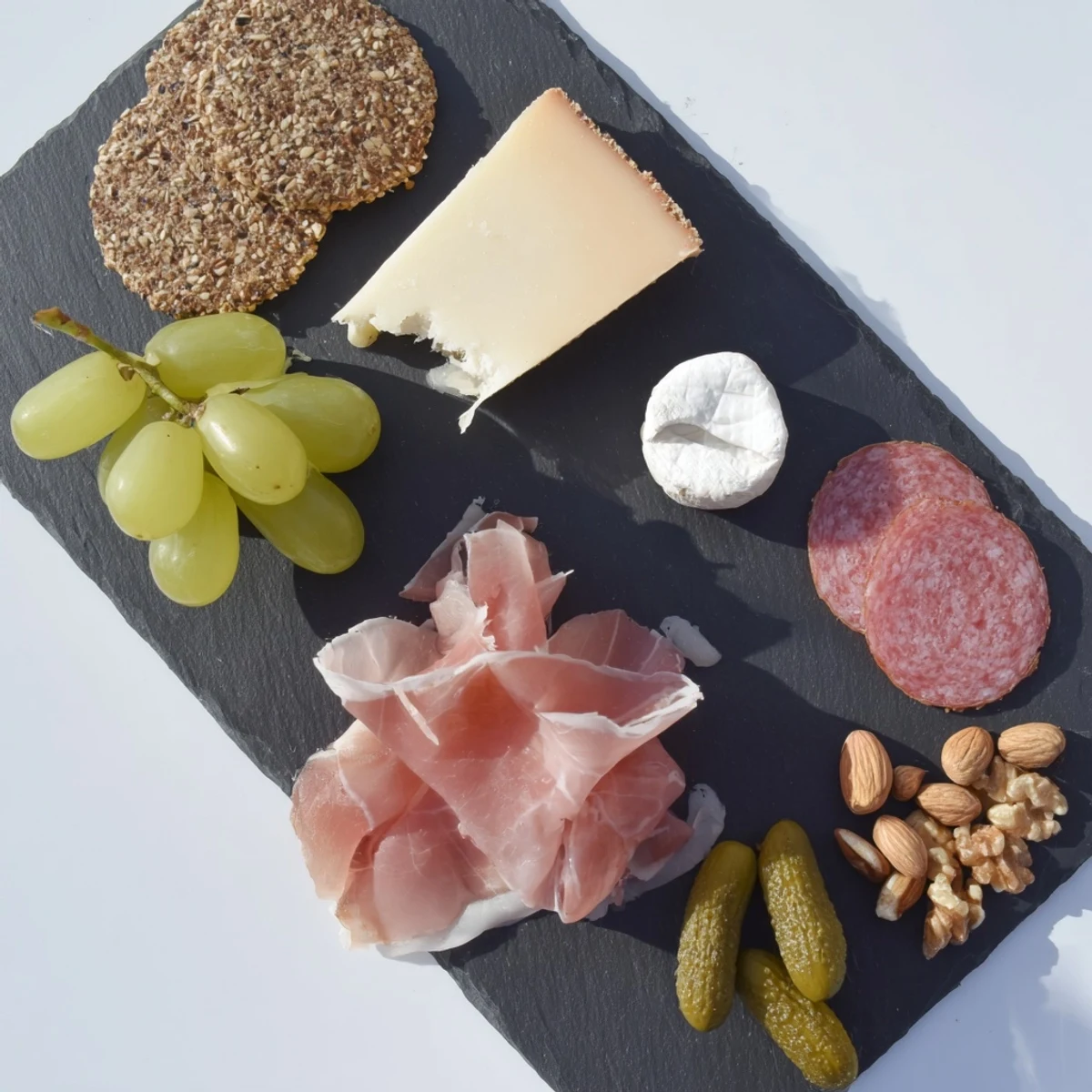 A single-serving Charcuterie Board for One, beautifully arranged with meats, cheese, grapes, and crackers.