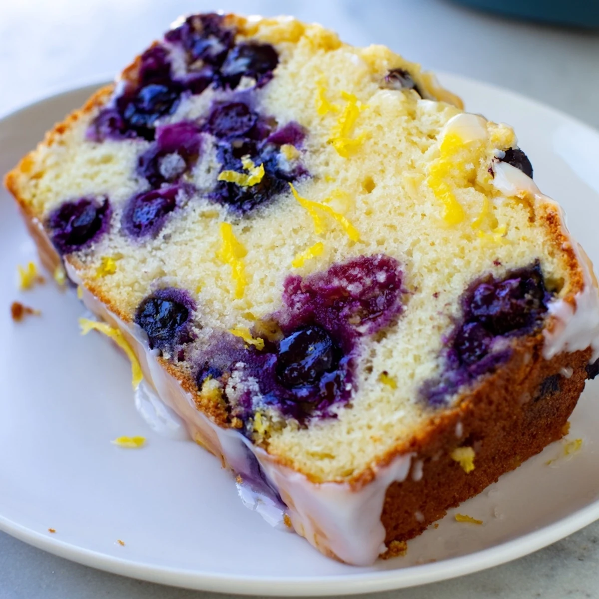 Fluffy Lemon Blueberry Yogurt Loaf, studded with juicy blueberries and drizzled with icing.