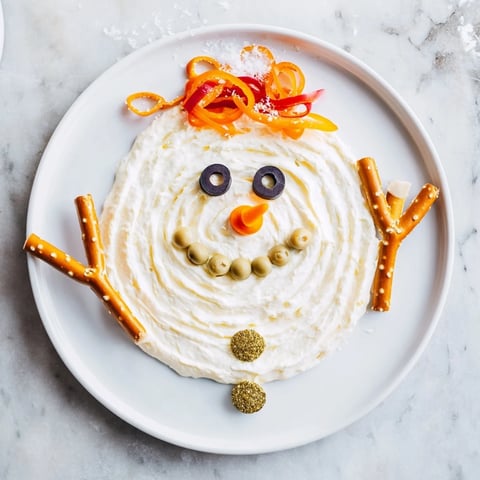 Creamy Melted Snowman Dip Bowl, a cheerful appetizer with olive eyes and carrot nose.