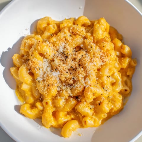 A warm bowl of Pumpkin Mac & Cheese, with a cheesy, pumpkin-infused sauce and perfectly cooked pasta.