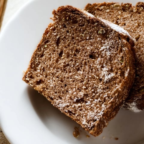 Dark, crusty Latvian Rupjmaize bread, ready to slice, with caraway seeds visible throughout, perfect for a sandwich.