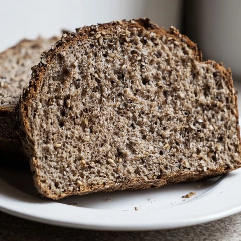 Crusty Estonian Leib Sourdough loaf, dark and enticing, speckled with caraway seeds after baking.