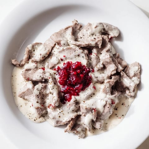Steaming Finnish Reindeer Stew, served in a rustic bowl beside vibrant red lingonberries; delicious!