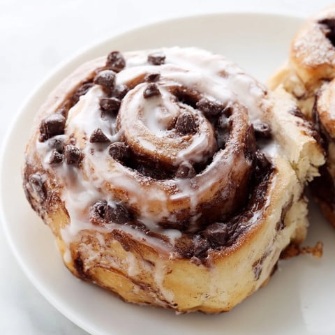 Fluffy cinnamon rolls swirled with rich Nutella and melty chocolate chips, drizzled with a sweet glaze.  