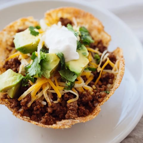 Warm, cheesy mini taco cups topped with fresh salsa, cilantro, and creamy sour cream.