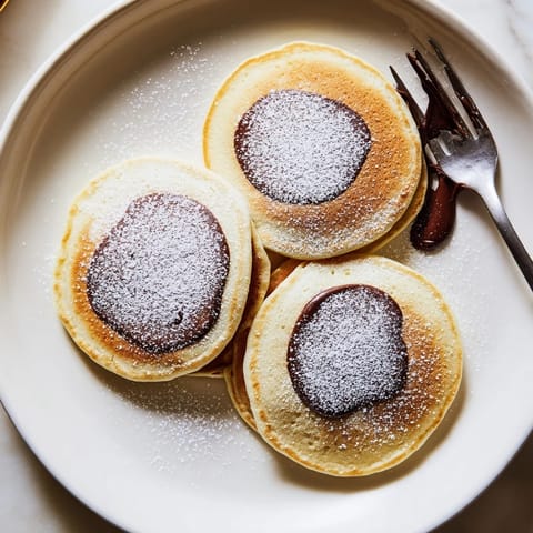 Warm Nutella Stuffed Pancakes bubbling on a griddle, with fresh banana slices and syrup ready to serve.