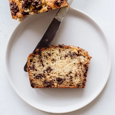 Golden-brown banana bread with chopped walnuts showcases a moist crumb and nutty aroma in this classic recipe.  