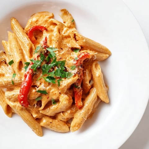 Close-up on Creamy Cajun pasta tossed in a glossy sauce, flecked with parsley and parmesan, steaming invitingly.