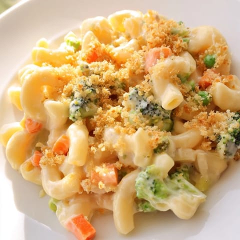A close-up of baked Garden Veg Mac and Cheese with melted cheddar and mozzarella, topped with golden panko crumbs in a rustic dish.