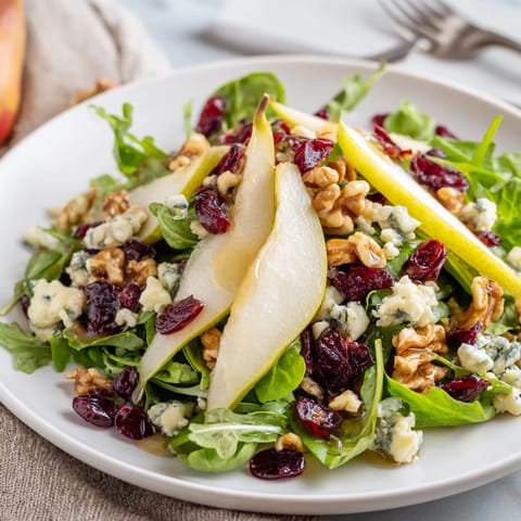 Golden toasted walnuts and dried cranberries add texture to this vibrant Pear Gorgonzola Salad, ready to be drizzled with honey-balsamic vinaigrette.
