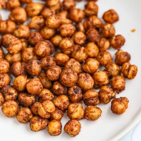 A close-up of crunchy chickpeas, seasoned with paprika and cumin, served in a rustic bowl for snacking.  