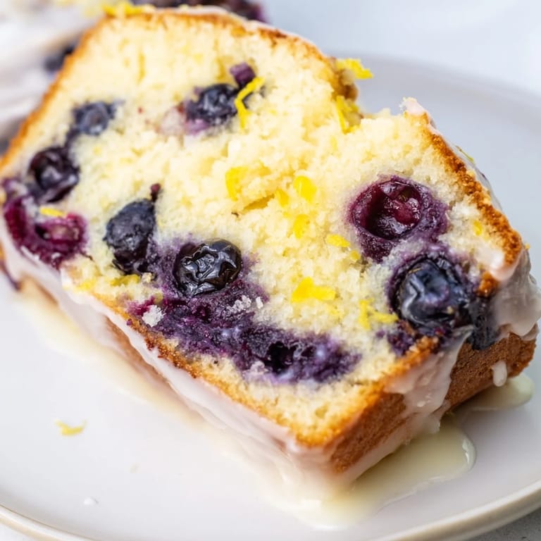 A golden slice of Lemon Blueberry Yogurt Loaf, perfect for breakfast with a cup of coffee.