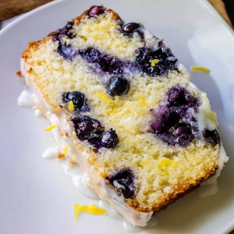 Close-up of a tender Lemon Blueberry Yogurt Loaf, showcasing bursting blueberries within a moist interior.