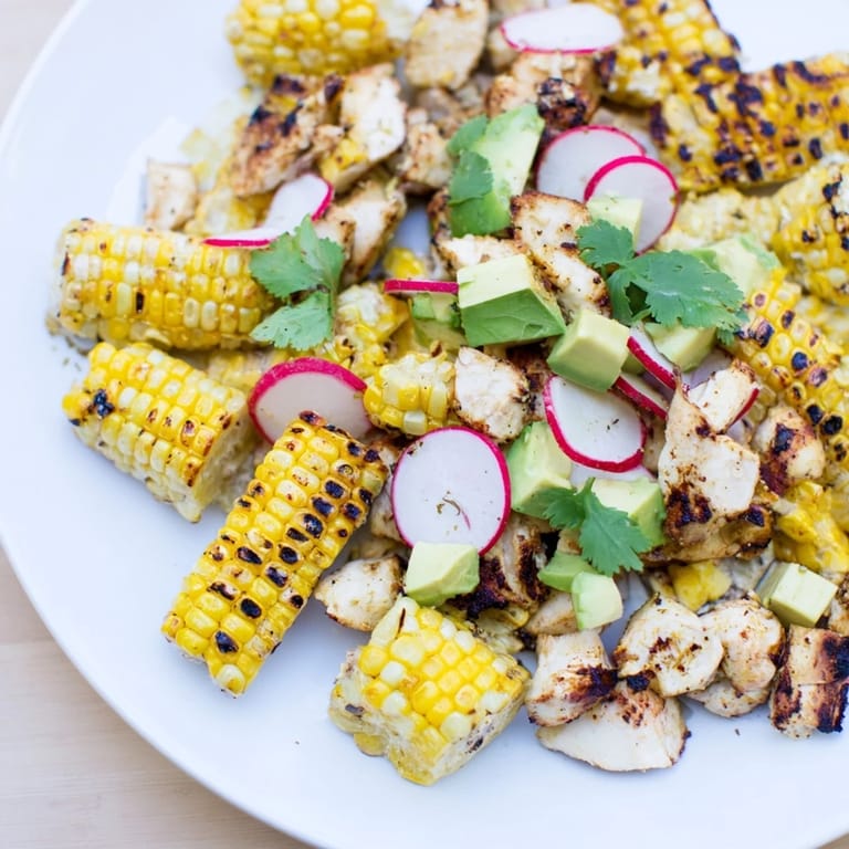 Close-up of Roasted Corn & Chicken Chopped Salad highlighting tender grilled chicken pieces, golden roasted corn kernels, and thinly sliced radishes in a rustic bowl.